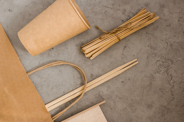 Eco goods, paper cups, supplies, sushi sticks, paper bag. Eco-friendly food items eco bags on gray background with copy space. Caring for nature and recycling concept.