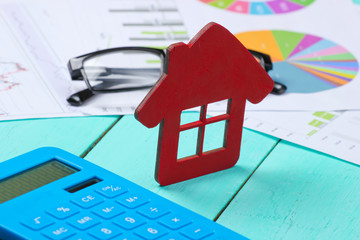 Analysis of the cost of buying or renting a home. Calculator with graphs and charts, house figurine...