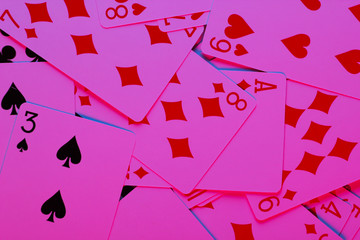 Playing cards in neon blue-pink light on black background. Game addiction. Poker