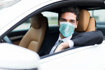 Handsome man driving his car wearing a mask, coronavirus concept