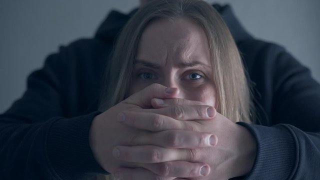 Victim of domestic violence. Violence against women,Scared woman with man's hand covering her mouth