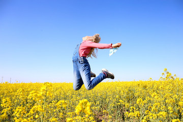 Girl jumping with a mask in her hands on a field background