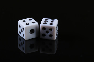Two dice on a black background with reflection