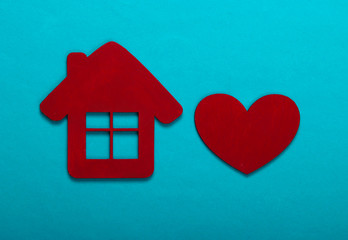 Fototapeta na wymiar House figurine and heart on a blue background. Top view