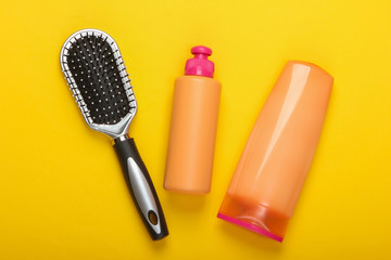 Shampoo bottles, hair conditioner, hair brushes on a pink background. Hair care. Hygiene. Beauty flat lay