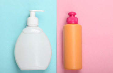 Obraz na płótnie Canvas Shampoo and soap bottles on blue pink background. Skin and hair care. Hygiene and cosmetics. Beauty flat lay. Top view