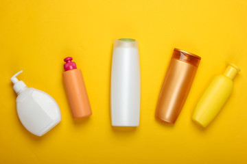 Shampoo bottles on yellow background. Hair care. Hygiene and cosmetics. Beauty flat lay. Top view