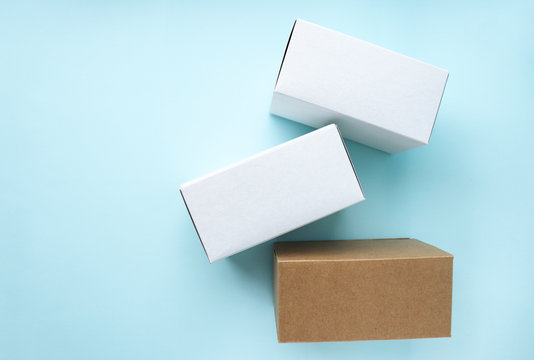 Three clean cardboard boxes are scattered on a blue background. Space for text. Selective focus.