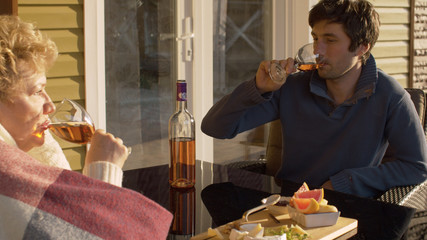 Young man drinking wine with senior woman