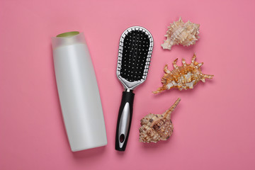 Bath beauty products. Bottle of shampoo, cockleshells, towel, hairbrush on pink background. Hair care. Top view. Flat lay