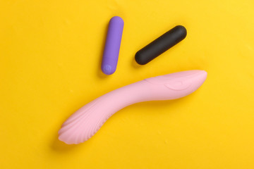 Female sex toys on yellow background. Sex stimulation. Top view