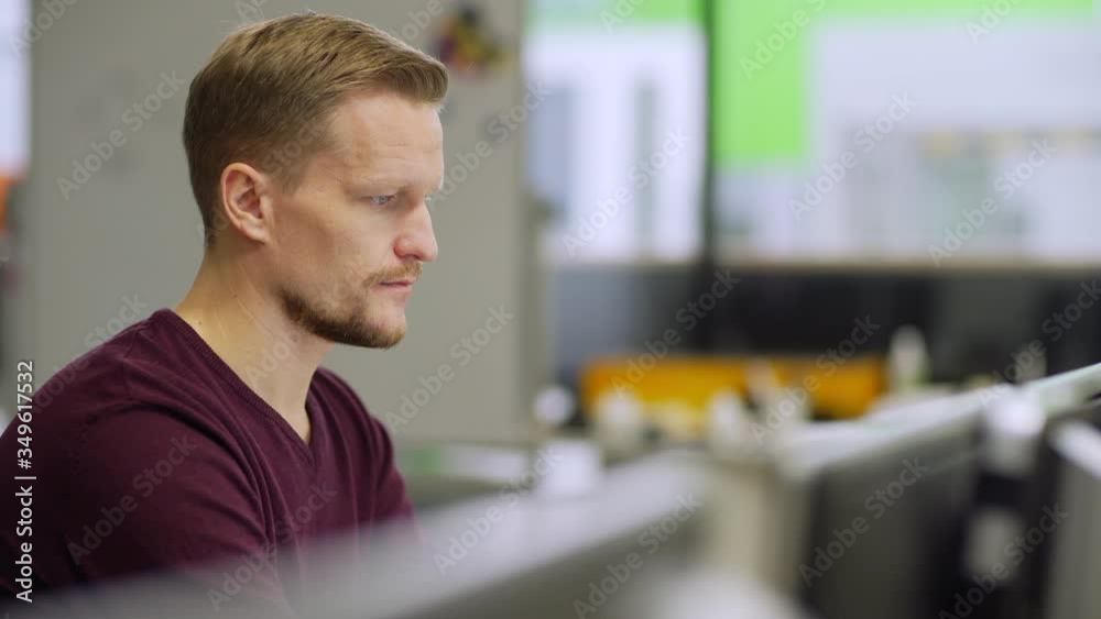 Wall mural tracking side view shot of focused middle aged engineer working on computer sitting at desk in labor