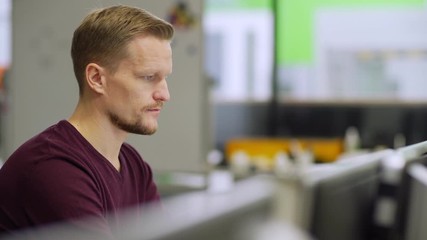 Tracking side view shot of focused middle aged engineer working on computer sitting at desk in laboratory