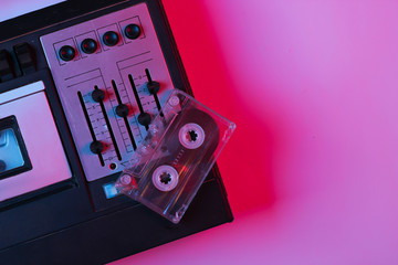 Retro audio tape recorder, audio cassette in pink bue gradient neon light. Retro media. 80s. Top view.
