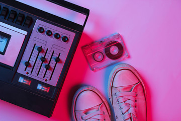 Retro audio tape recorder, audio cassette, sneakers in pink bue gradient neon light. Retro media....