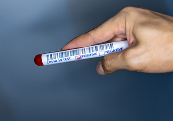 Obraz premium Hand holding a test tube with blood for covid 19 testing. Test tube used for corona virus testing. Covid 19 positive result