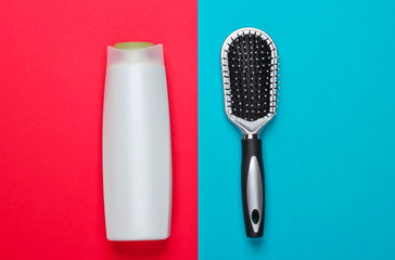 Hair Care Products. Shampoo bottle and hair brush on a red-blue background. Top view