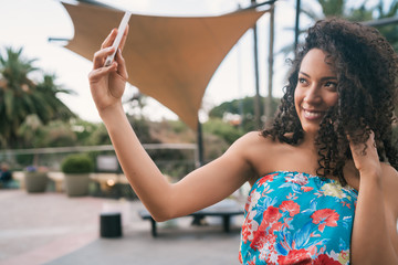 Afro American latin woman taking a selfie with phone.