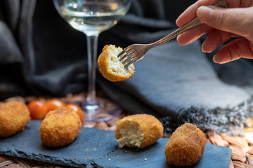 Croquettes presented on slate with a broken piece on fork ready to eat. Horizontal view.
