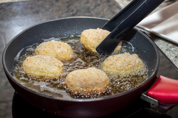 Croquettes frying in a pan with olive oil .Horizontal view.