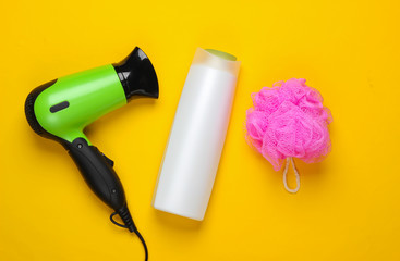 Bath Set, products and devices for hair care. Hair dryer with bottle of shampoo, bath bottle on yellow background. Top view