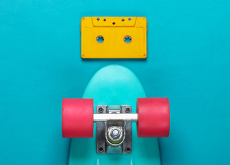 Cruiser board and retro audio cassette on blue background. 80s. Top view. Minimalism. Pastel color...