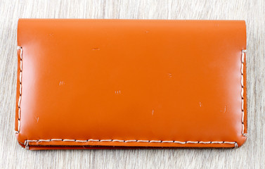 Brown leather wallet on wooden board background..