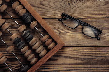 Vintage abacus with glasses on a wooden background. Top view.
