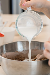hands pouring milk into bowl