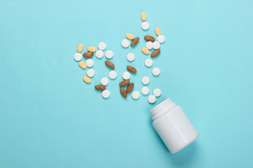 Bottle with different pills on a blue background. Top view