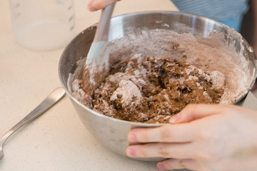 hands mixing dough in a bowl