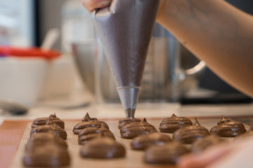 close up of pipping chocolate macaroon