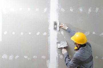 interior decoration construction furniture builtin.Plasterer in working uniform plastering the wall...