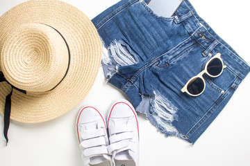straw, wide brim hat, denim shorts with a phone and sunglasses in pockets and gumshoes isolated on...