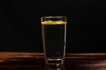 lemon in glass of water on black background