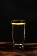 lemon in glass of water on black background