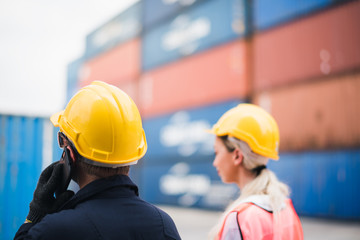 Closed up at hand of young man worker Check and control loading freight Containers use phone at commercial shipping dock. see from back side point to container. Cargo freight ship import export