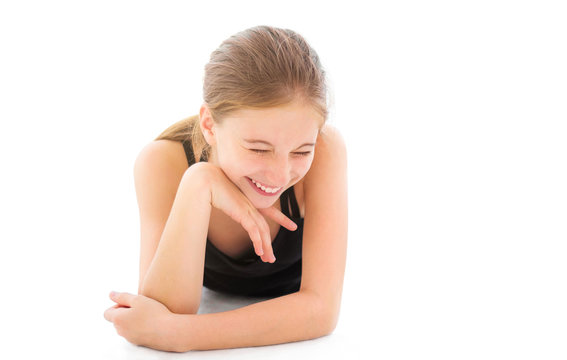 Cute laughing girl lying on a floor isolated on a white background