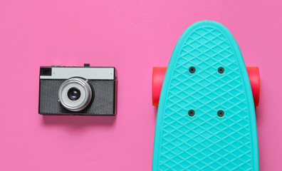 Retro set with blue skateboard and retro camera on pink background. Studio shot. Youth lifestyle. Top view