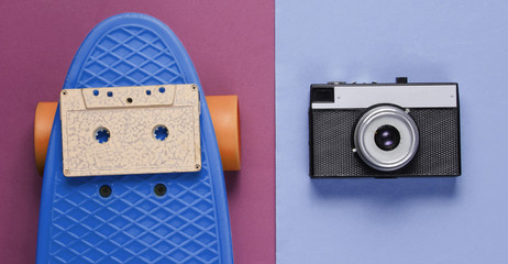 Retro set with blue skateboard with audio cassette and retro camera on colored background. Studio shot. Youth lifestyle. Top view © splitov27
