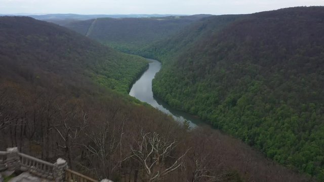 Aerial camera flying out over the Coopers Rock sandstone overlook showing the mountains and Cheat River below.