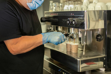 A worker preparing coffee with mask and gloves. Not recognizable people.