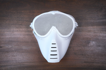 White painted airsoft mask with wooden background