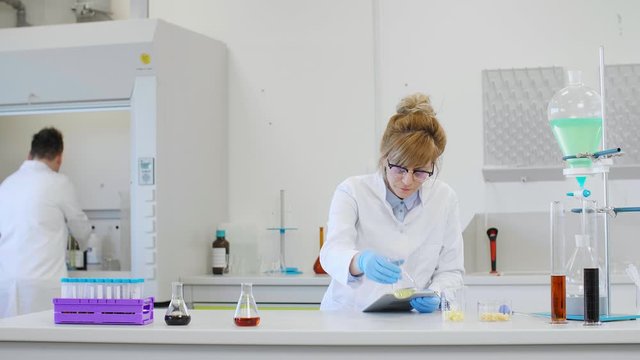 Chemist working with hemp CBD oil and tablet in laboratory