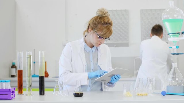 Chemist working with hemp CBD oil and tablet in laboratory