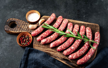 raw sausages with ingredients on a cutting board on a stone background with copy space for your text
