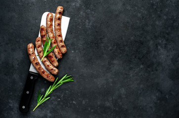 
grilled sausages with ingredients over a meat knife on a stone background with copy space for your...