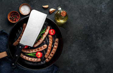 Obraz na płótnie Canvas grilled sausages with tomatoes and rosemary in pan on a stone background with copy space for your text