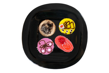 Dessert pieces of cake on a black plate isolated on white. View from above.
