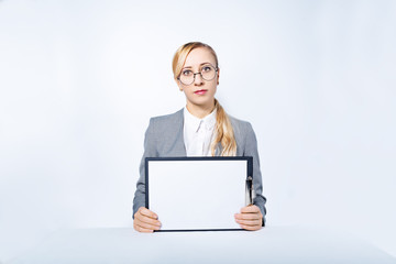 Blonde business woman in a suit is sitting at a table on a white background